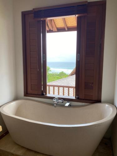 a bath tub in a room with a window at Bombora Balangan Resort in Ungasan