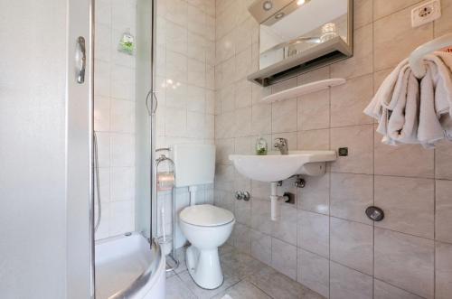 a bathroom with a toilet and a sink and a shower at Rooms & Apartments Hegic in Zadar