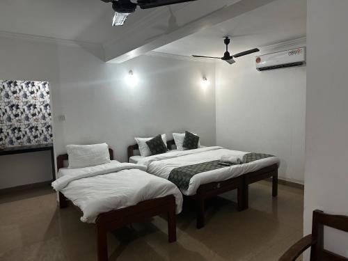 two beds in a room with white walls at Ocean Way Guest House in Baga