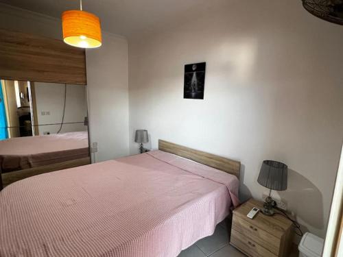 een slaapkamer met een bed met een roze deken bij Conmal Penthouse In Mellieha Bay in Mellieħa