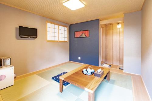 a living room with a table and a tv at Kyoto KaedeHotel Kamogawa in Kyoto