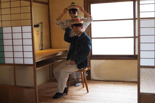 a man sitting on a chair with a hat on his head at 岡邸 in Tonosho