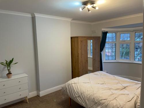 a bedroom with a bed and a dresser and windows at Super Convenient 2 Double Bed apartment for Central London - 30 seconds walk to platform train station and 19 mins to London Waterloo in London