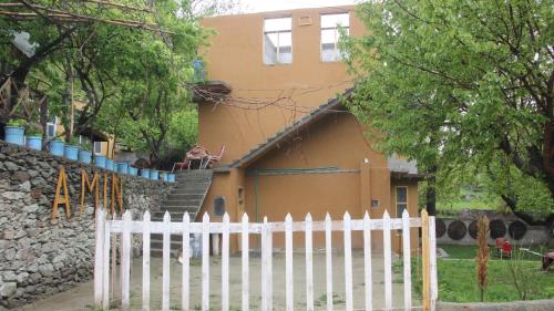 a white fence in front of a house at Rakaposhi Amin Hotel & Restaurant Pissan Hunza Nagar Gilgit Baltistan in Gilgit