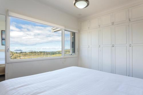 1 dormitorio con cama blanca y ventana en Ocean Vista by the BnB Collection en Albany