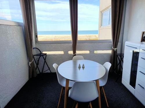 uma mesa branca e cadeiras num quarto com uma janela em Studio Vue Mer 100 m de la plage em Port Leucate