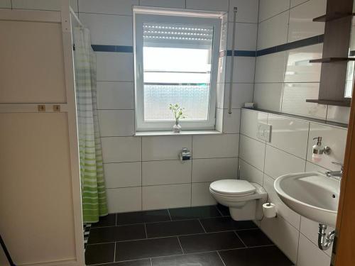 ein Bad mit einem WC, einem Waschbecken und einem Fenster in der Unterkunft Tempel-Inn Konrad-Adenauer-Straße 4 in Werlte