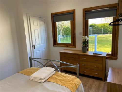 a bedroom with a bed and a dresser and a window at Chalet on the Green - Self Contained with parking. in Inshes