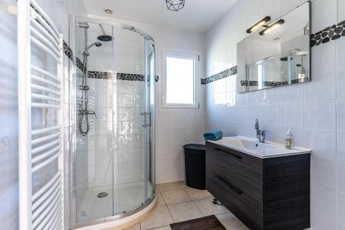 La salle de bains est pourvue d'une douche en verre et d'un lavabo. dans l'établissement Le Grand Barbot - Maison pour 4 proche plage, à Gujan-Mestras