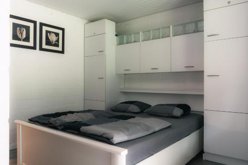 Cama en habitación con armarios blancos en vakantie-hengelhoef en Houthalen