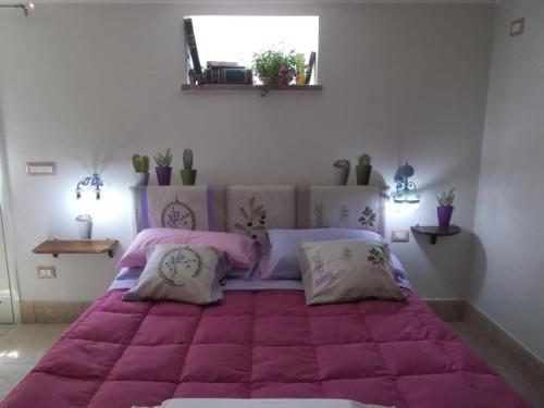 a bedroom with a large pink bed with pillows at casa di campagna dal pozzo in Sorso