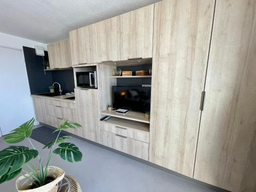 - une cuisine avec des placards en bois et un four micro-ondes dans l'établissement Le Studio de la Digue, à Wissant