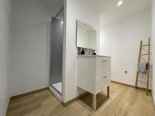 een badkamer met een witte kast en een spiegel bij L'échappée flamande in Hazebrouck