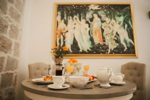 a table with plates and cups and a painting on the wall at Elephant in my room in Dubrovnik