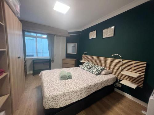 een slaapkamer met een bed en een groene muur bij Vibes Coruña- Estancia moderna en Eiris in A Coruña