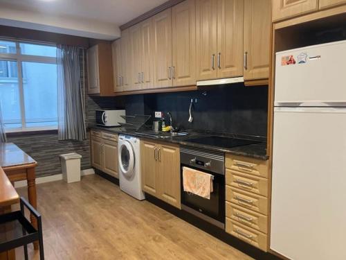 a kitchen with a white refrigerator and a dishwasher at Vibes Coruña- Estancia moderna en Eiris in A Coruña