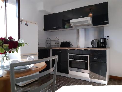 a kitchen with black cabinets and a table and a microwave at n6 appartement de Vacancorse Maison U Canale in Speloncato