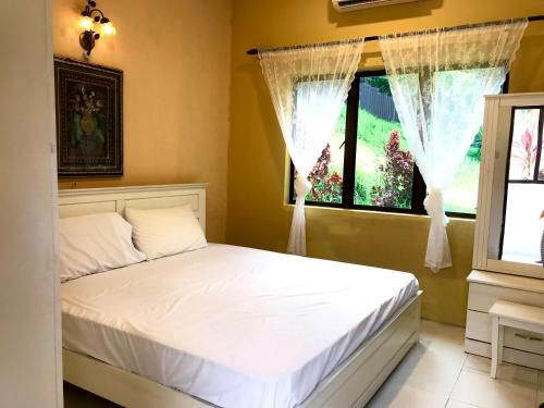 a bedroom with a white bed and a window at Eco Resort Beverly Hills in Ipoh