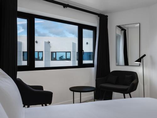 タモンにあるHotel Tano Guamのベッドルーム1室(椅子2脚、ベッド1台、窓付)