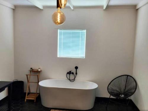 a white bath tub in a room with a window at Noordoewer Self Catering Chalets in Noordoewer