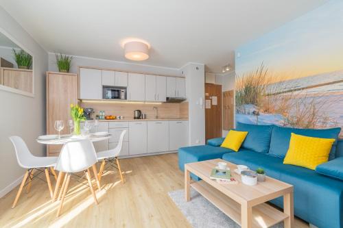 ein Wohnzimmer mit einem blauen Sofa und einem Tisch in der Unterkunft Apartamenty NCNK Stegna Forest in Stegna