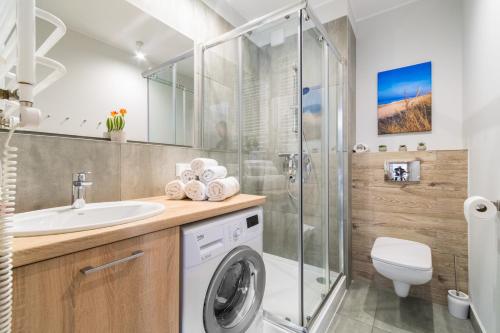 ein Badezimmer mit einer Waschmaschine und einem Waschbecken in der Unterkunft Apartamenty NCNK Stegna Forest in Stegna