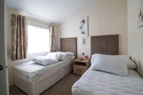 a bedroom with two beds and a window at Luxury 6 Berth Lodge With Wifi At Broadland Sands In Suffolk Ref 20011cv in Hopton on Sea