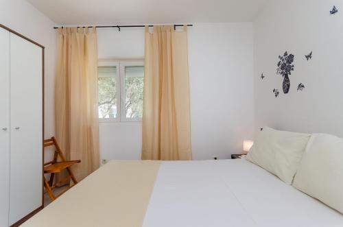 1 dormitorio con cama blanca y ventana en Apartments Durdica F en Punat