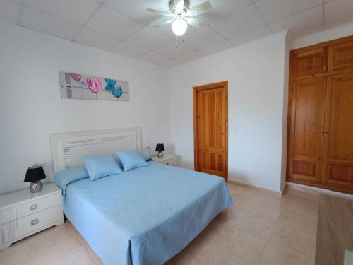 Schlafzimmer mit einem blauen Bett und einem Deckenventilator in der Unterkunft Villa Noemi, con piscina privada in Calpe