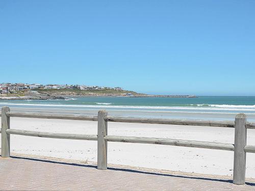 a wooden fence on a beach with the ocean at Sea Glimpse Yzer in Yzerfontein