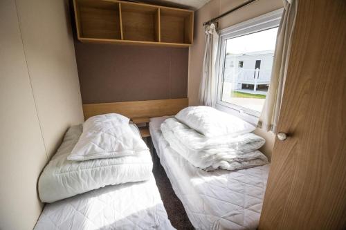 two beds in a small room with a window at 8 Berth Caravan At Broadland Sands Holiday Park In Suffolk Ref 20140bs in Hopton on Sea