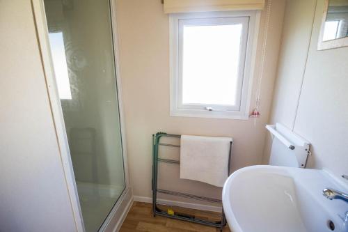 a bathroom with a shower and a sink and a window at 8 Berth Caravan At Broadland Sands Holiday Park In Suffolk Ref 20140bs in Hopton on Sea