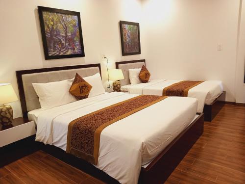 two beds in a hotel room with two lamps at IRIS HILL VILLA in Thôn Dương Xuân Hạ