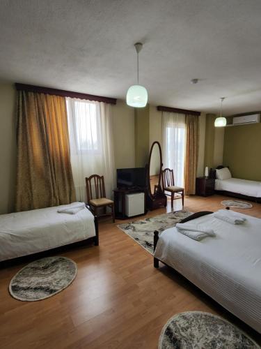 a hotel room with two beds and a living room at Guesthouse Bimbli in Pogradec
