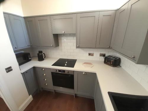 a kitchen with white cabinets and a black appliance at Kirkcudbright Holiday Apartments - Apartment C in Kirkcudbright
