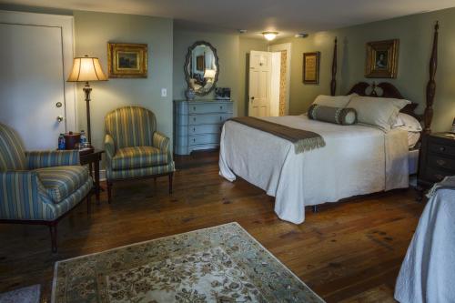 a bedroom with a bed and two chairs and a mirror at Eliza Thompson House, Historic Inns of Savannah Collection in Savannah