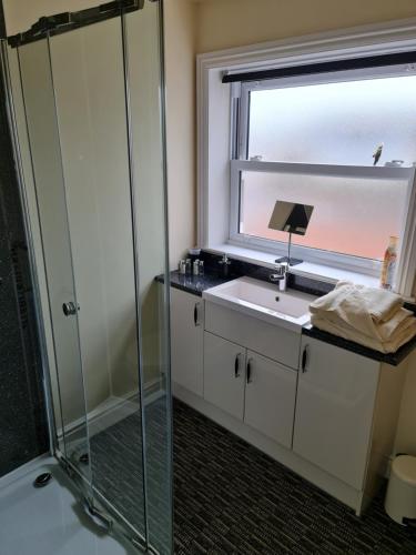 a bathroom with a shower and a sink and a window at Marden guest house in Weymouth