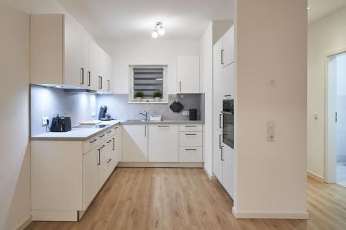 a white kitchen with white cabinets and a wooden floor at Wohnen auf Zeit & Ferien in Wehr - Apartment Sand in Wehr