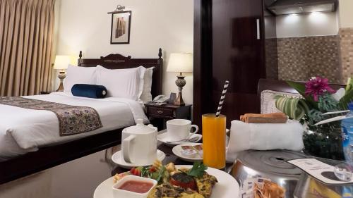 een hotelkamer met een bed en een tafel met eten bij Heritage Luxury Suites All Suite Hotel in Lahore