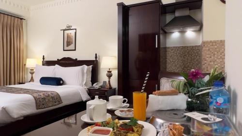een hotelkamer met een bed en een tafel met eten bij Heritage Luxury Suites All Suite Hotel in Lahore
