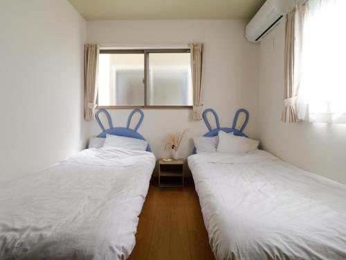 two twin beds in a room with a window at 貸別荘 ウサギの郷 in Fujikawaguchiko