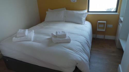 a large white bed with two towels on it at Buckie - 2 Bed Luxury Apartment in Wick