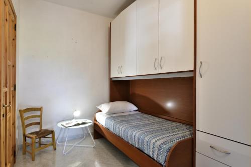 1 dormitorio pequeño con 1 cama y 1 silla en 3 - Casa con giardino Lotzorai - Sa Crai Apartments Sardinian Experience, en Lotzorai