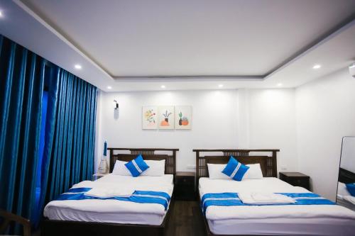 two beds in a room with blue curtains at Wonderland Homestay - Venuestay in Vĩnh Phúc