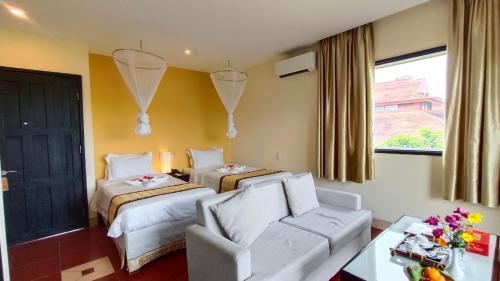 une chambre d'hôtel avec deux lits et un canapé dans l'établissement Hue Riverside Boutique Resort & Spa, à Hue