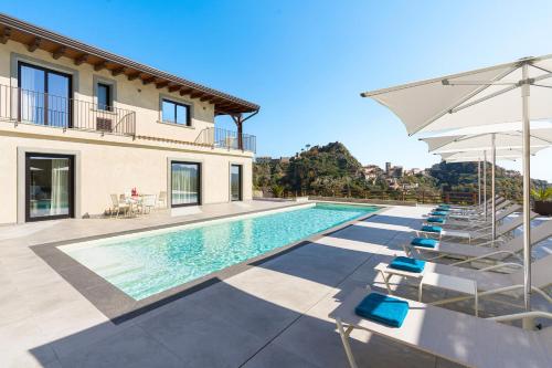 a villa with a swimming pool with chairs and an umbrella at Zagara Bianca in Savoca 