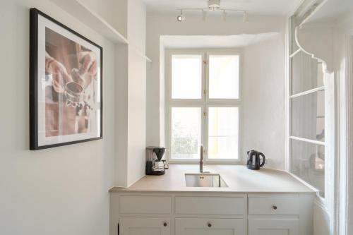 a white kitchen with a sink and a window at Cozy Flats in Heart of Copenhagen Near Strøget & Højbro Plads in Copenhagen