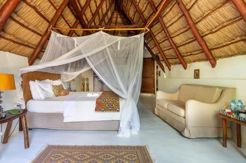 LEMON BEACH LODGE Vilankulo في فيلانكولوس: غرفة نوم بسرير واريكة