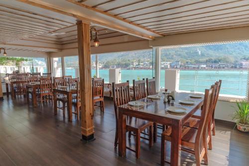 a restaurant with tables and chairs and a view of the water at Yog Niketan By Sanskriti in Rishīkesh