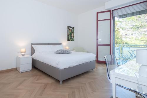 ein weißes Schlafzimmer mit einem Bett und einem Balkon in der Unterkunft Appartamento Rossini - Volta 4 in Cernobbio